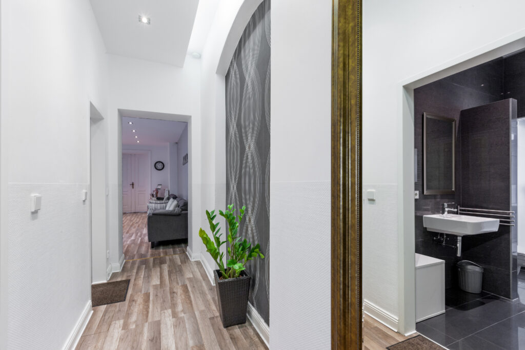 Blick in einen Flur mit Holzboden, weißen Wänden und Türrahmen